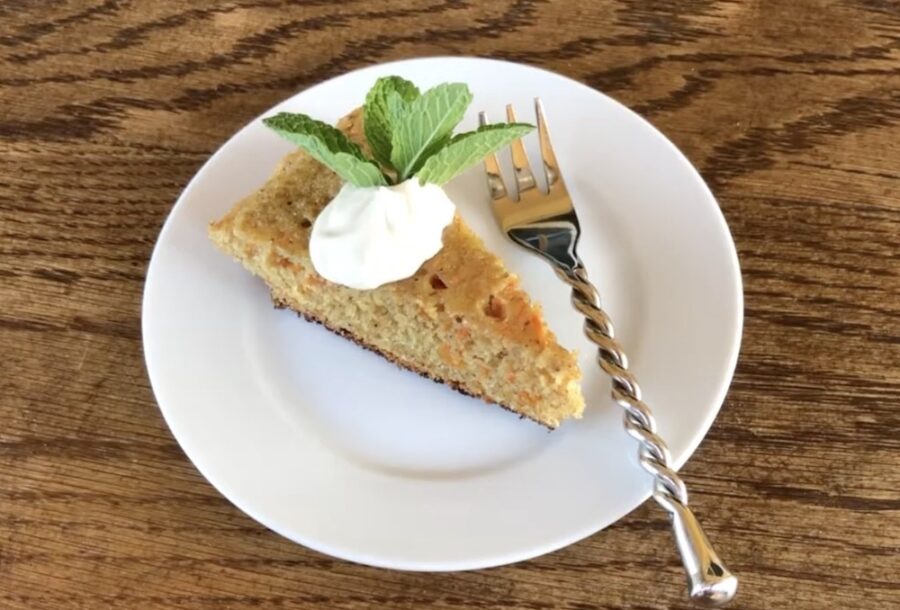 moist looking Carrot Cake slice on plate with dollop of whipped cream