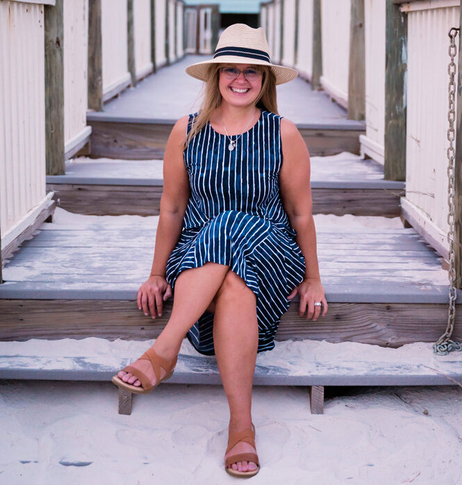 Kelly Taylor sitting on steps in sand at beach in Florida